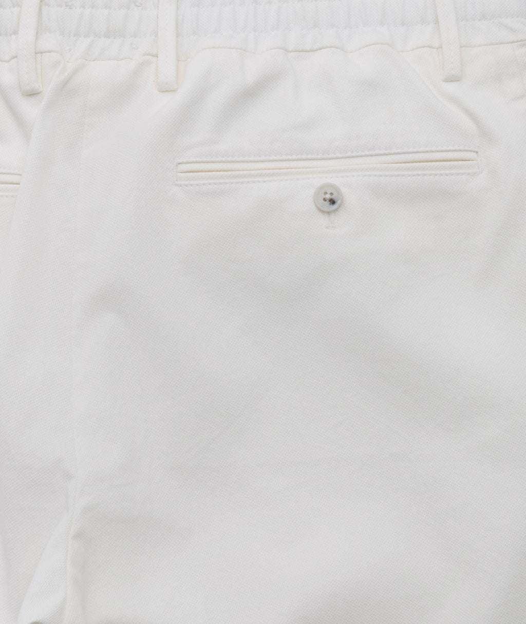 Model is wearing UNTUCKit Stretch Cotton Hybrid Pant in Cream. 